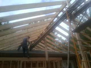 Rafters going up over a new addition with a worker on the wall in Eckley