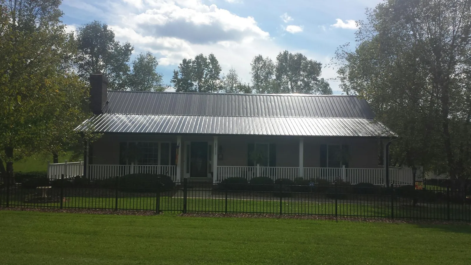 Gray metal roof on a brick ranch with a full width front porch — Gutter Guard Installation work by our crew in Eckley