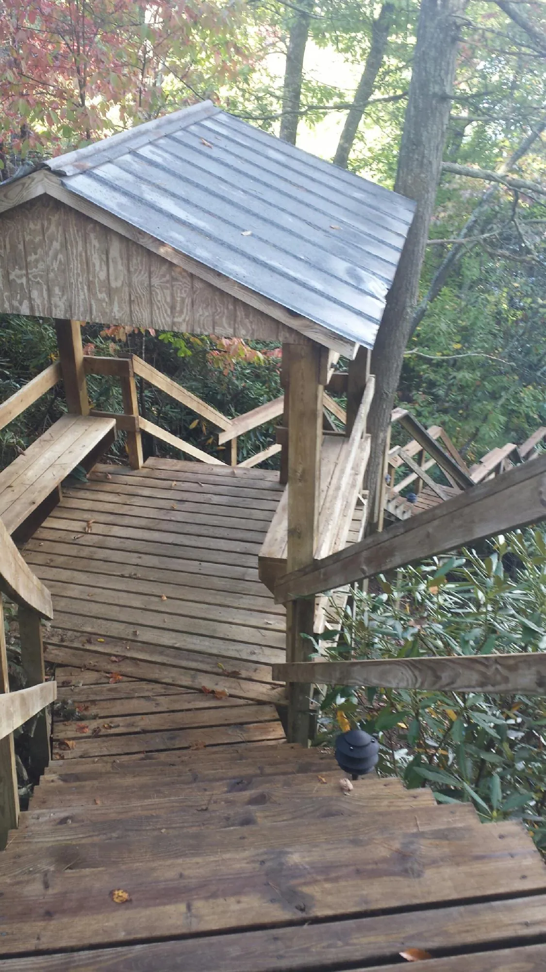 Metal roofed shelter over wooden steps on a wooded walkway — Skylight Repair & Installation work by our crew in Eckley