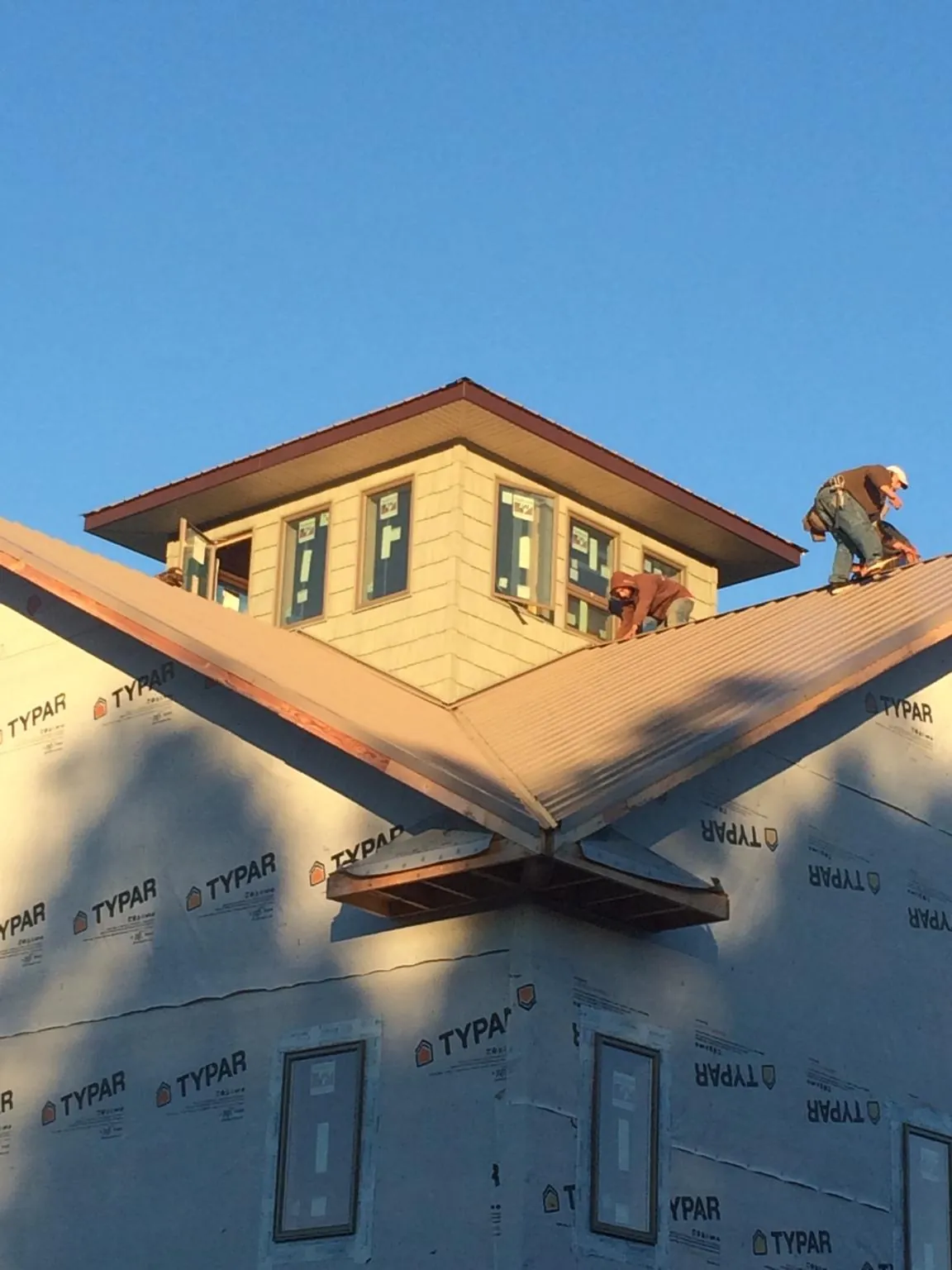 Roofers working around a rooftop cupola on a new metal roof at sunset — Roof Waterproofing in Eckley by Roofing Brothers